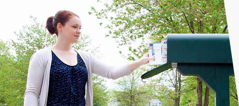 A standard curbside mailbox on a tree-lined street.